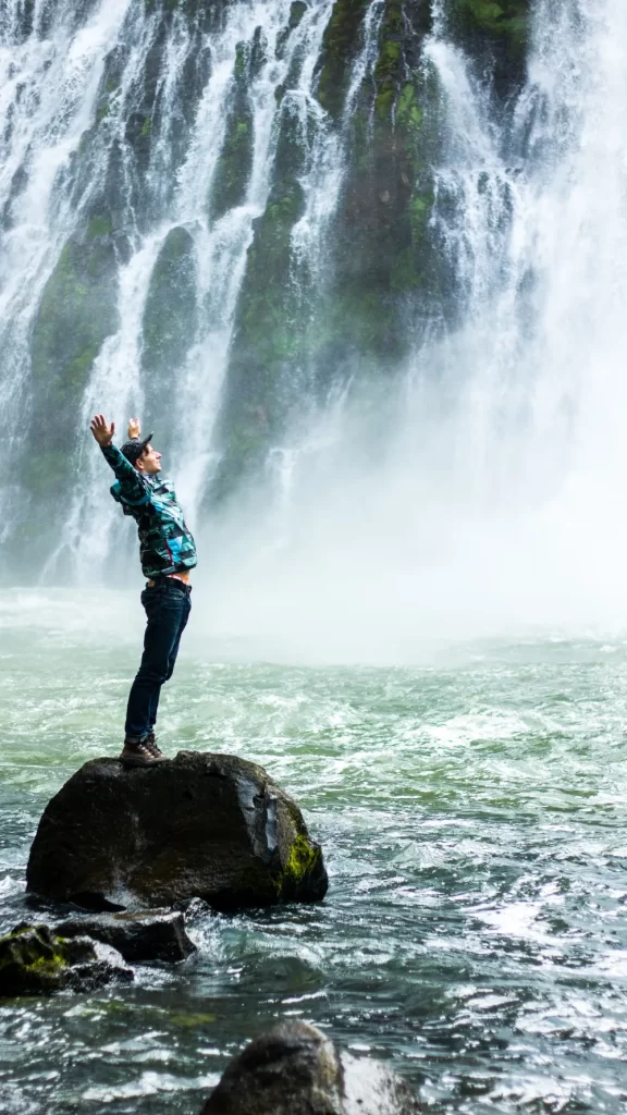 man standing on rock with arms up